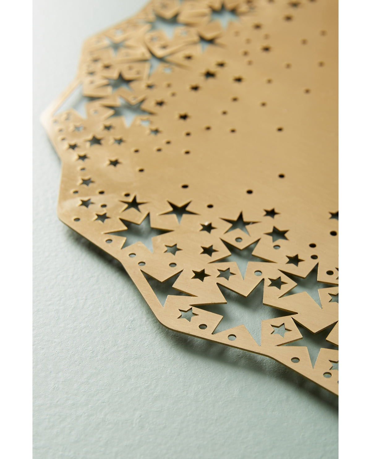 Close-up of the laser-cut stars on the gold Celestial Placemat Charger - Ariana Ost