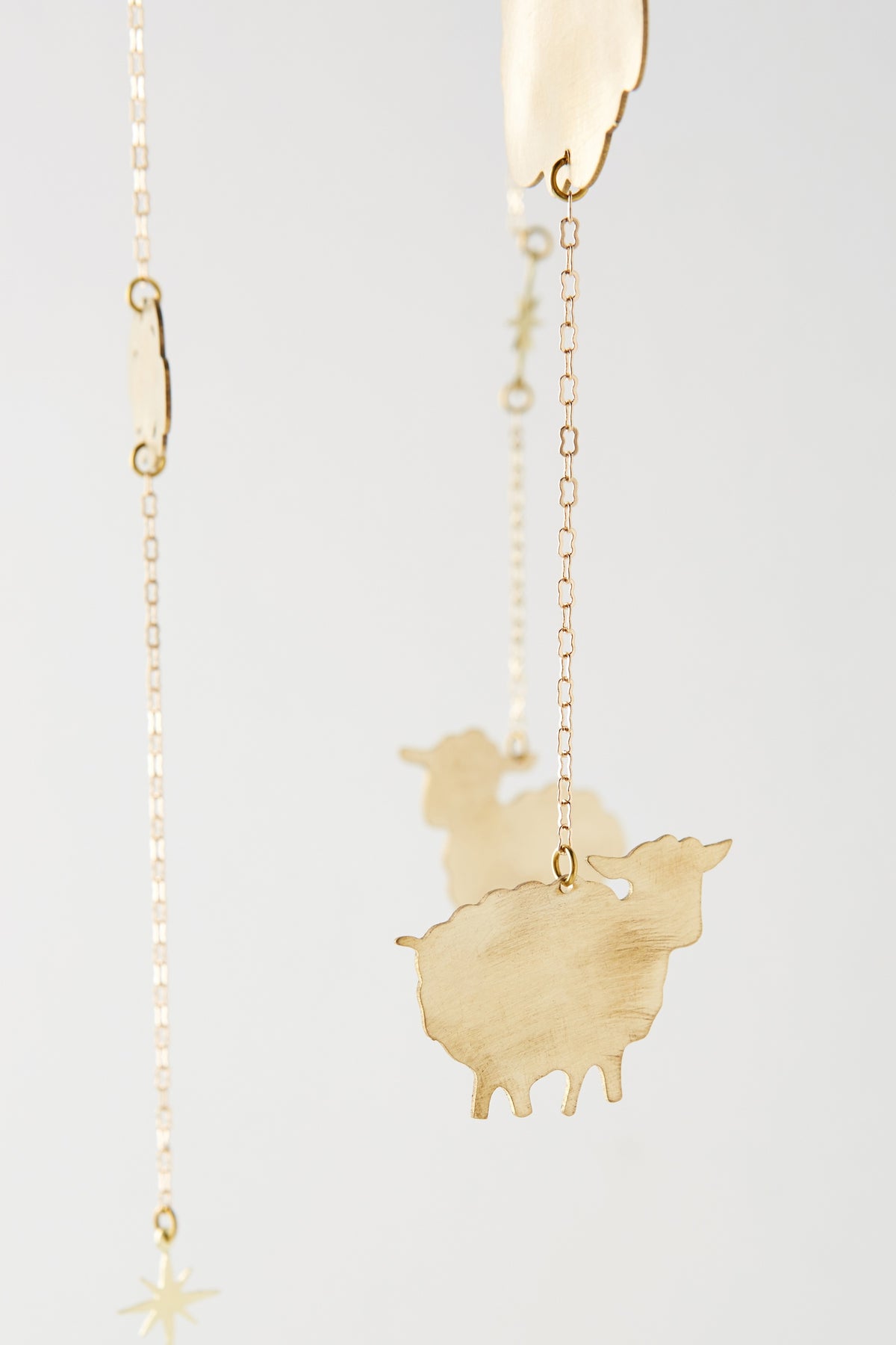 Close-up of the hand-cut brass sheep and star charms on the Counting Baby Sheep Mobile - Ariana Ost