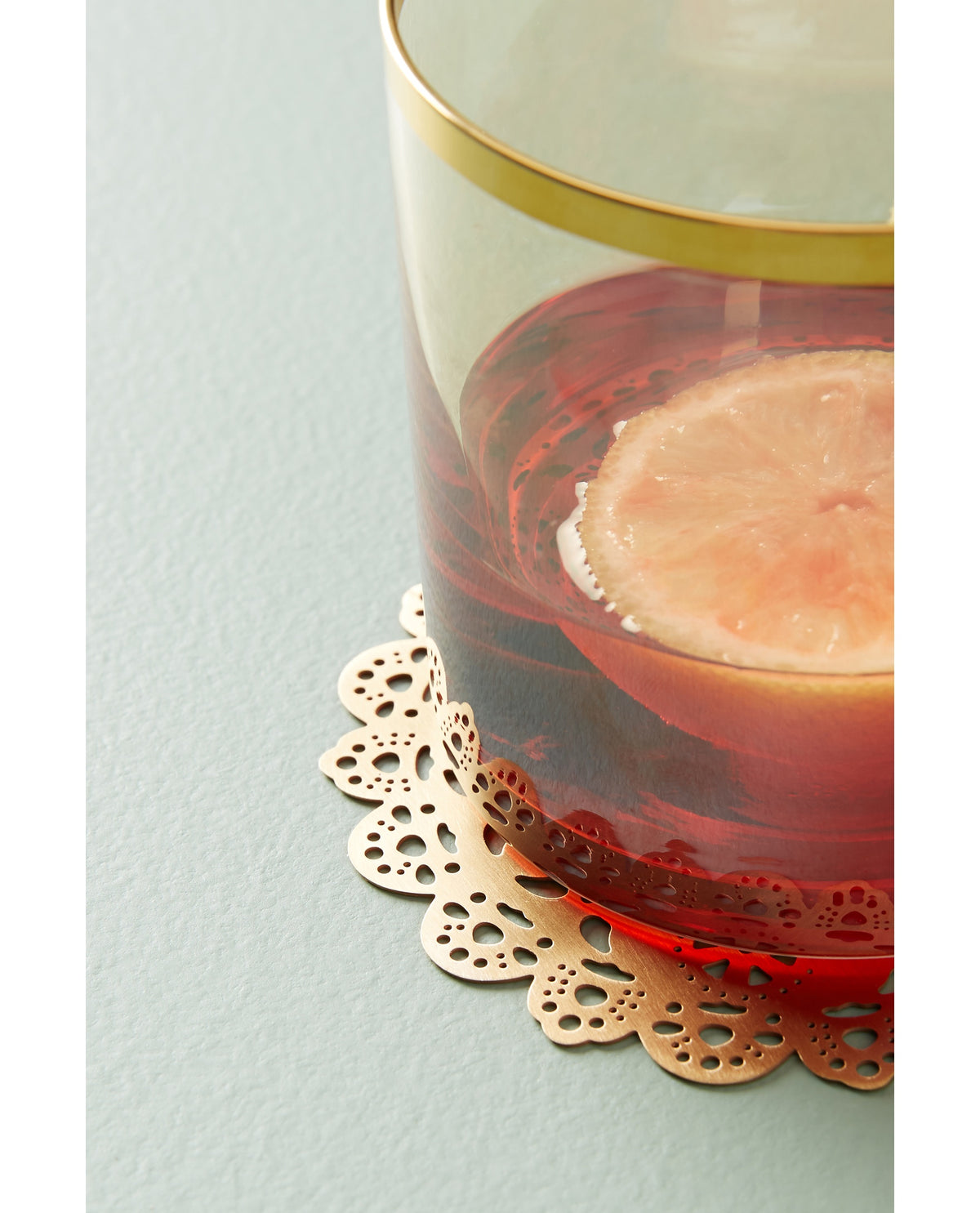 Gold Eyelet Doily Coaster under a cocktail with a grapefruit slice - Ariana Ost