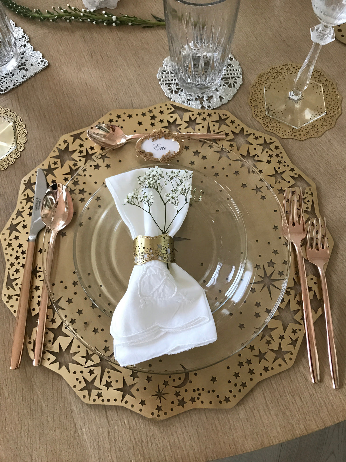 Gold Celestial Placemat Charger under a glass plate with a Twinkling Star Napkin Ring, rose gold flatware and a Celestial Coaster under a crystal goblet - Ariana Ost